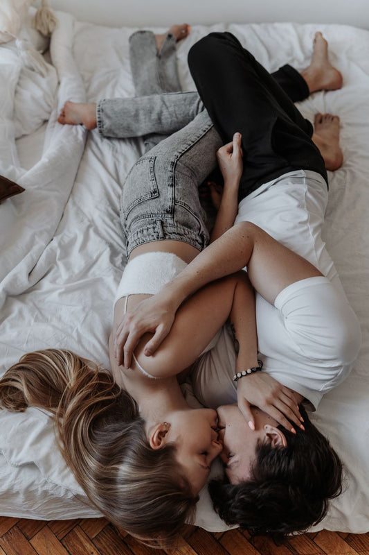 Couple kissing tenderly on a bed in soft daylight, intimate connection