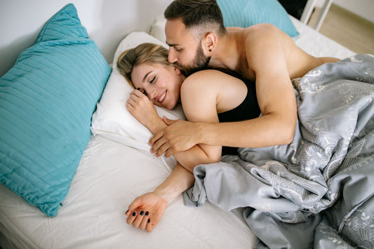 Smiling man resting affectionately beside his partner in bed, cuddling in a relaxed afterglow moment