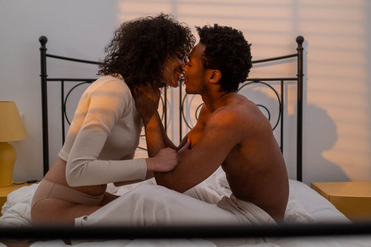 Couple sitting close on a bed forehead to forehead, warm affectionate intimate bedroom light