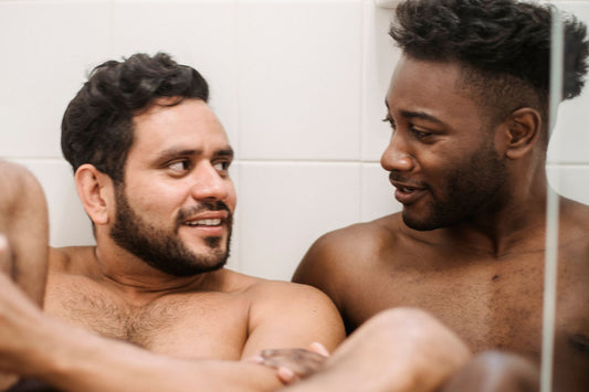 Two smiling shirtless men relaxing close together, a warm and intimate moment