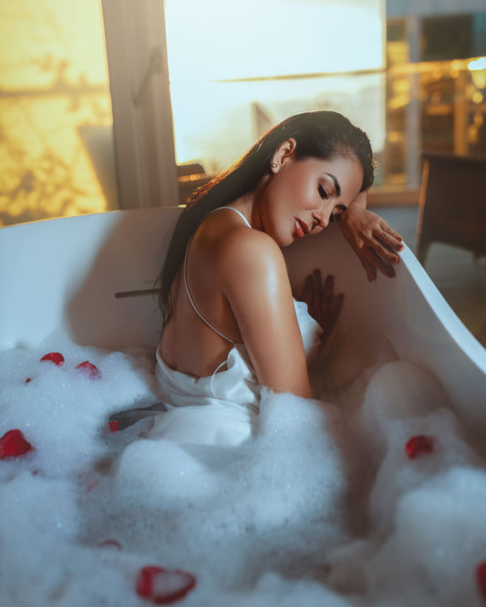 Woman relaxing in a warm bubble bath with rose petals, eyes closed in a calm sensual moment